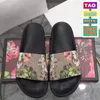 2022 Herrkvinnor tofflor m￤n kvinnor platt tofflor glider blomma svarta blommiga glidmode sandaler med dammv￤ska skor l￥da strandreglage lyx l￤der mans sandal