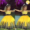 2015 Färgglada gula bollkakor Golvlängder Pageantlackar för små tjejer Gyllene applikationer Billiga blommaflickor klänningar med svart sash