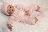 Ręcznie robiony 22-calowy lalek silikonowy odrodzony dziecko jest ubranym różową tkaninę piękną noworodka zabawka kłama i siedzi