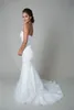 La robe de mariée de style trompette comprend une taille basse, un décolleté en cœur, une jupe fluide en organza et une robe de mariée en dentelle avec cordon