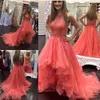 2018 Nuevos vestidos de fiesta de coral Vestidos de noche elegantes sin mangas con cuello en V Cremallera trasera Vestido de fiesta por encargo con gradas Hi-Lo con apliques de encaje